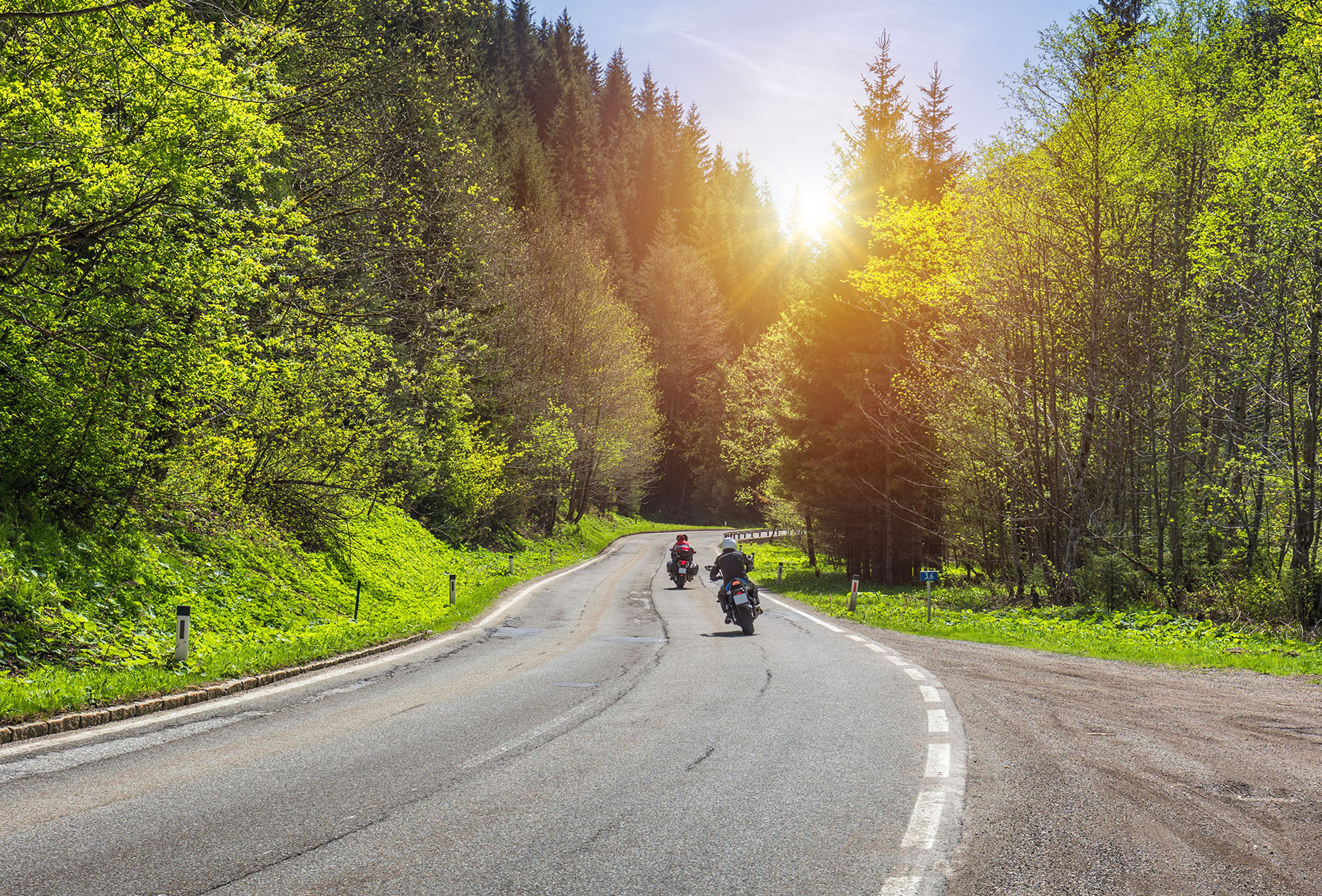 Bikers on mountainous highway, biker on the road in sunset light riding on curve road pass across Alpine mountains, extreme lifestyle, freedom concept. Austria, Alps